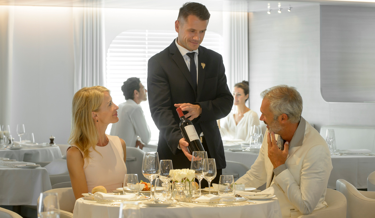 Server showing wine to customers