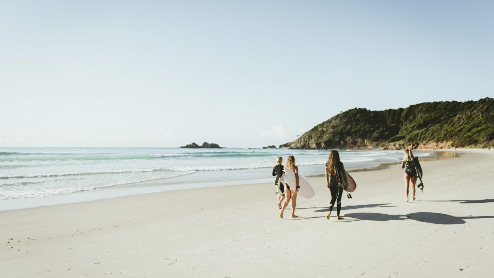 Surfers walking down the sea shore with their boards
