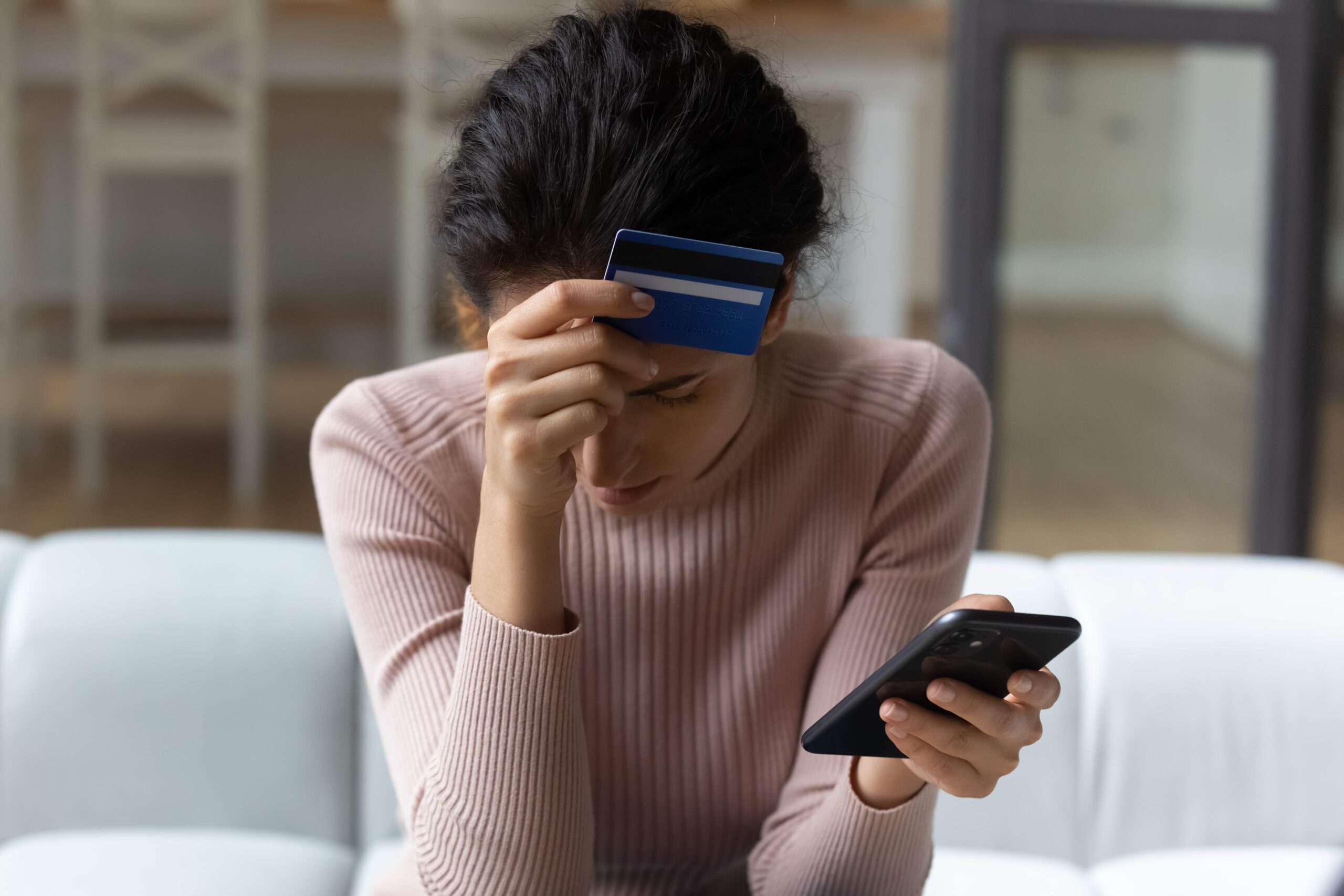 women holding credit card to her head after being scammed