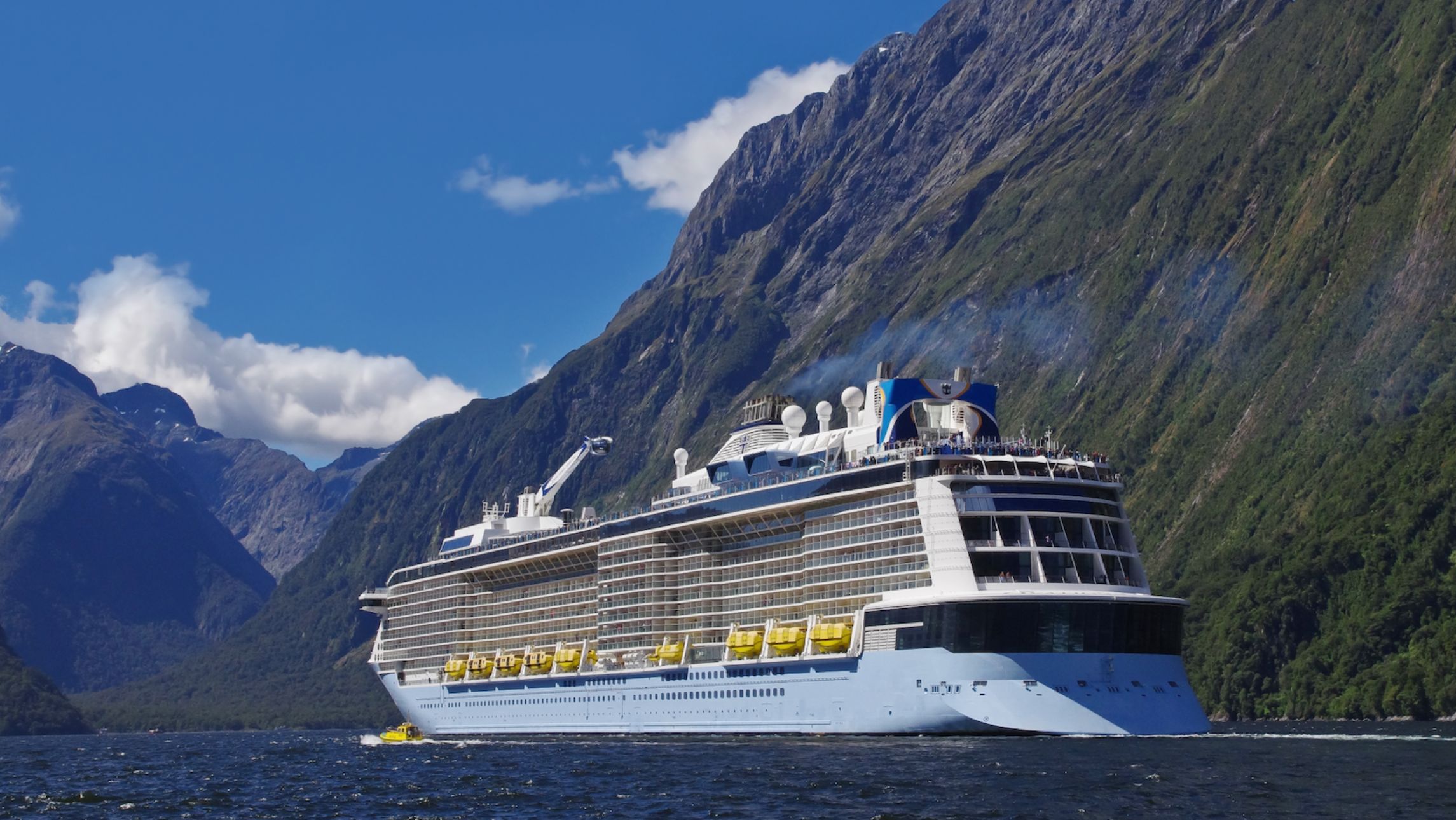 Cruise ship cruises through the mountains at Milford Sound.